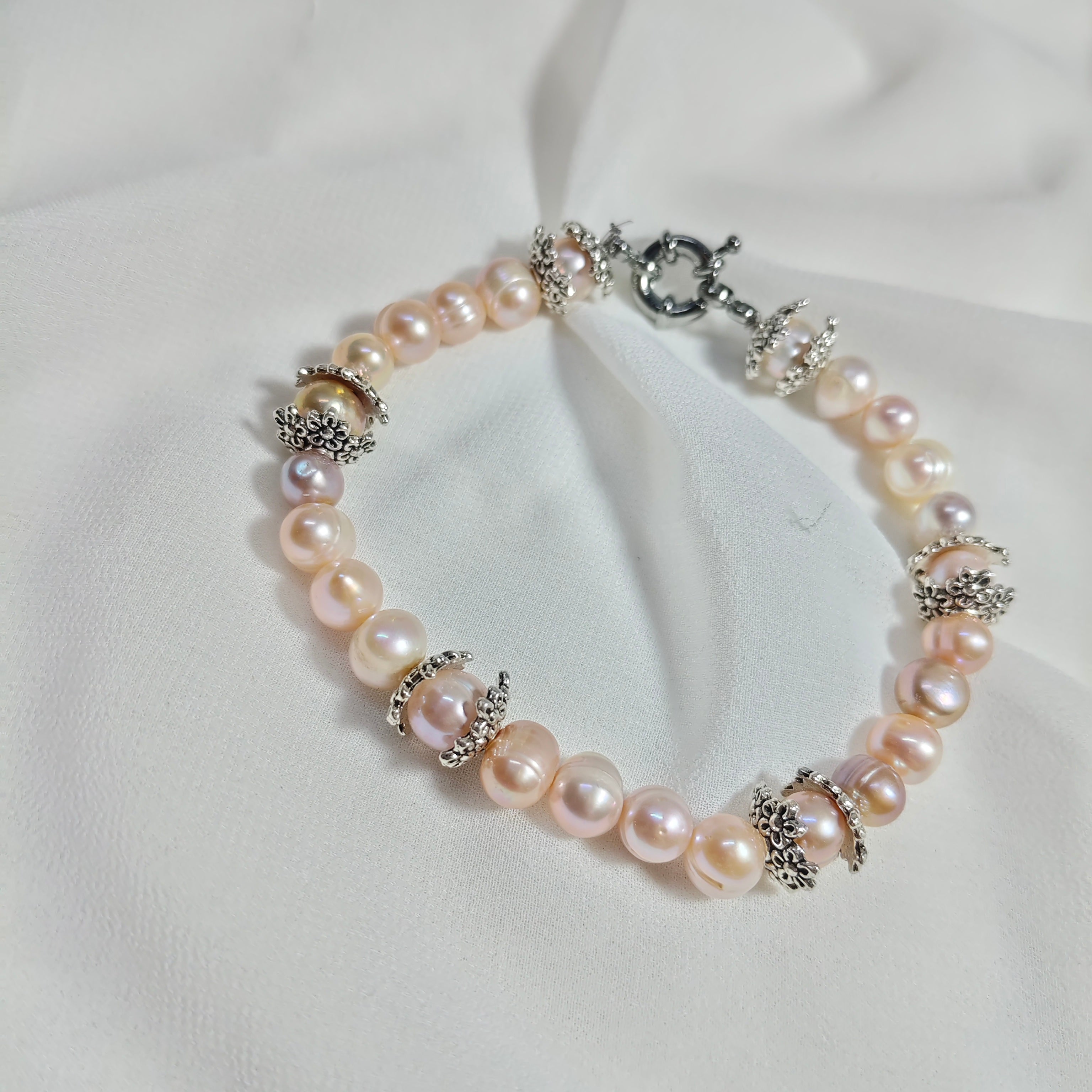 Bracelet perles de culture roses et séparateurs en argent 925 ciselés sur fond blanc
